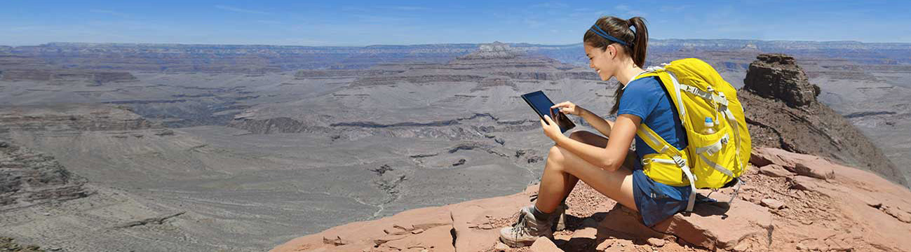 Una chica en la montaña leyendo en su tablet