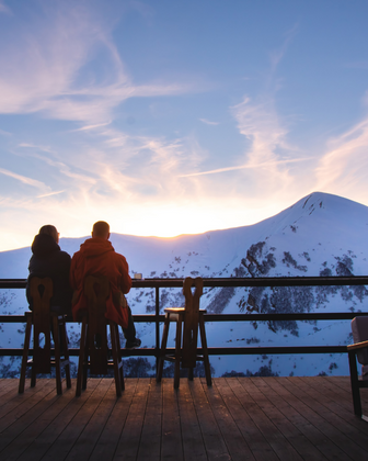 una pareja sentados viendo las montañas nevadas